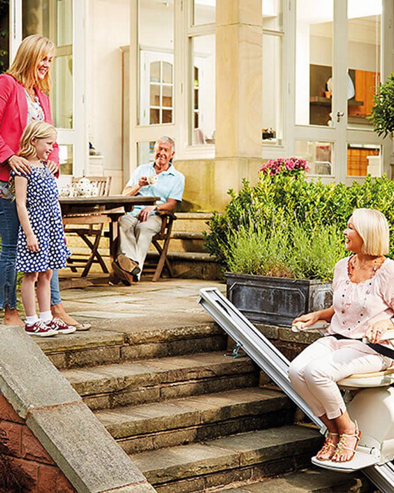 lady using the acorn outdoor stairlift whilst chatting to friends
