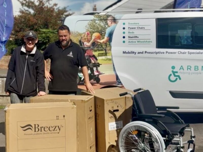 Staff from arb mobility stood next to a van with wheelchairs next to them