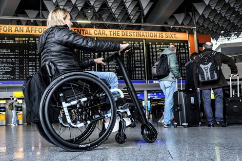Lady sitting in quickie manual wheelchair with empulse F35 power add on attached